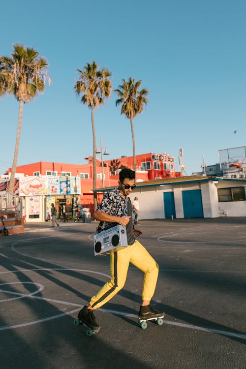 Woman in Black and White Button Up Shirt and Yellow Pants Skating on Gray Concrete Floor