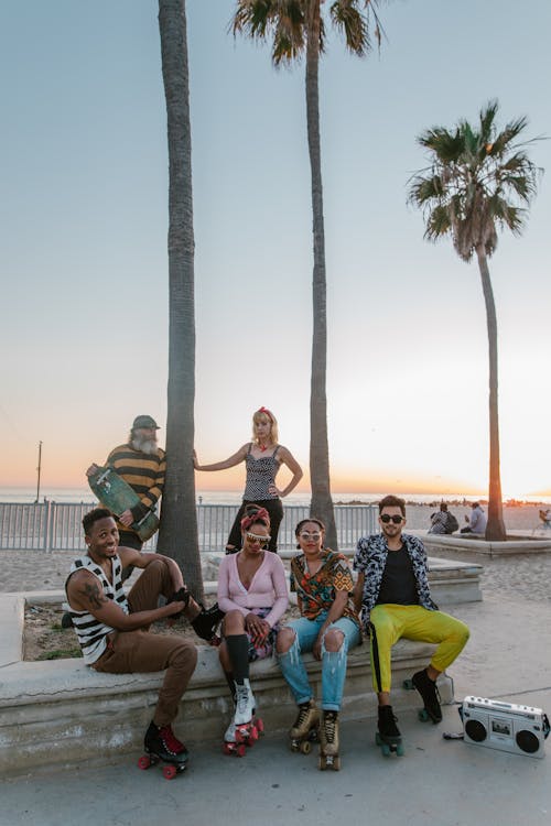 People Sitting on Concrete Bench Near Palm Tree