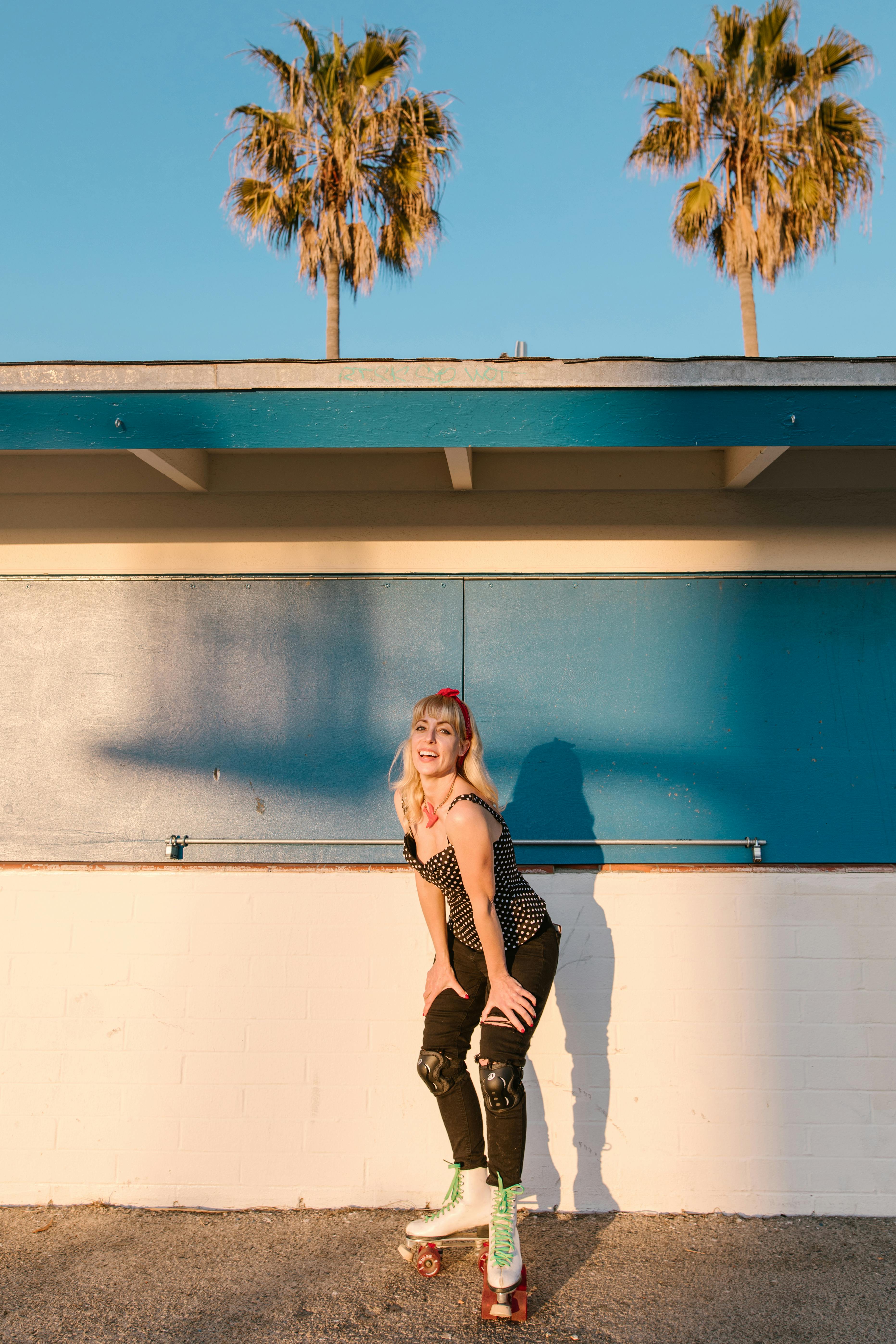 Blonde woman roller skating by palm trees during a sunset outdoors.