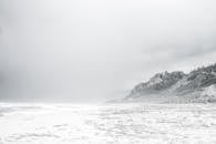 宁静的冬季海滩上，雾蒙蒙的悬崖与变幻的天空，捕捉了大自然的静谧