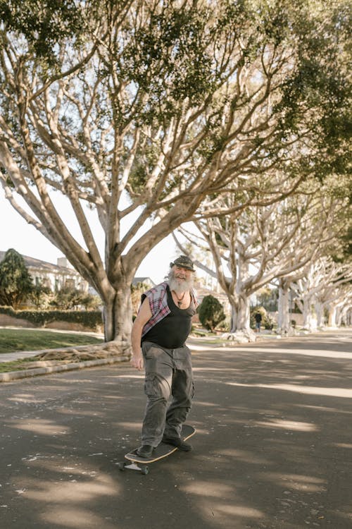 An Elderly Man Skateboarding Near Trees