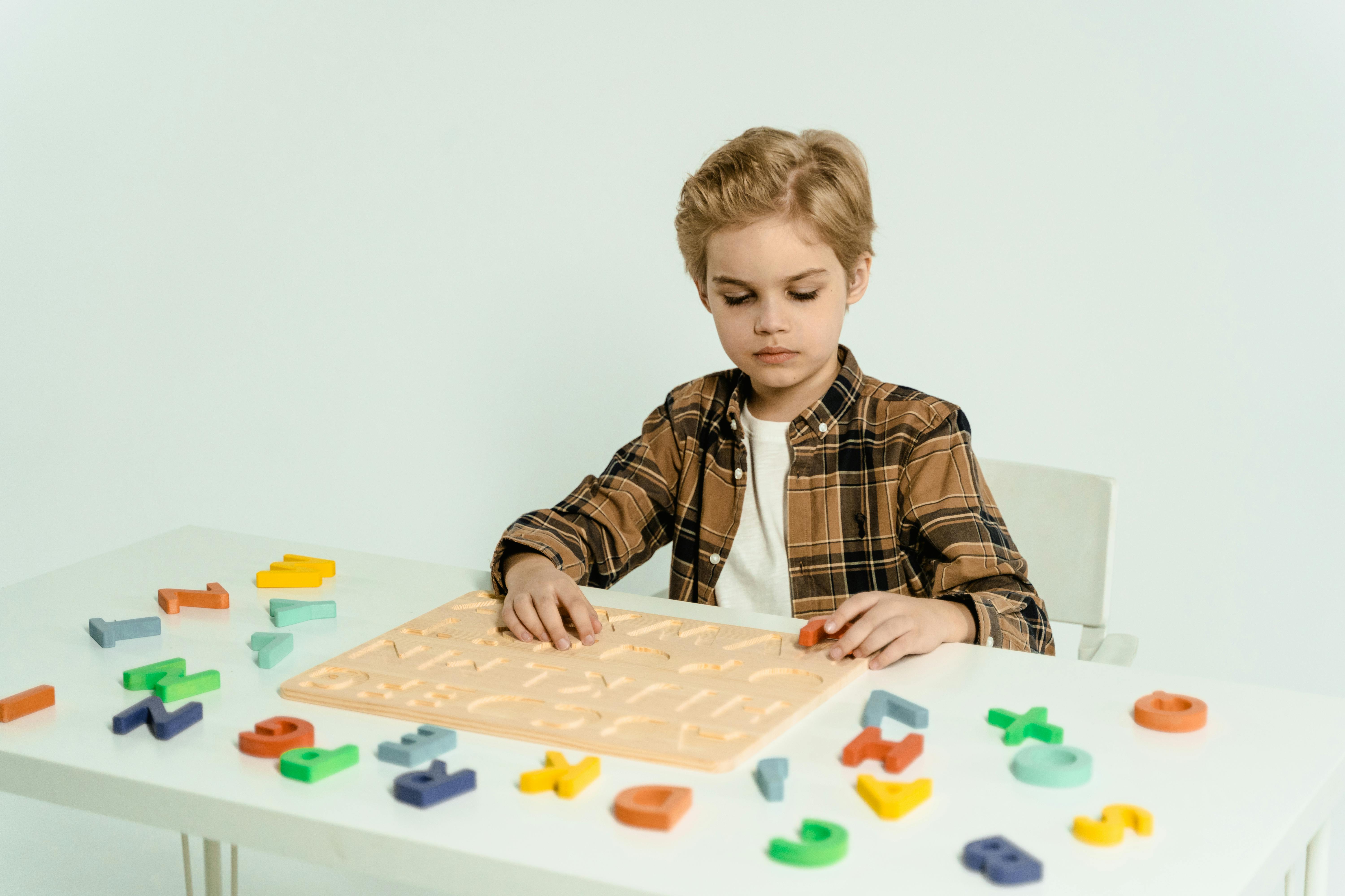 blonde boy learning alphabet with plastic letters