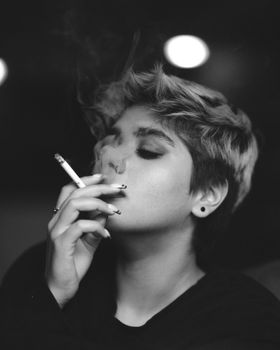 Black and white portrait of a woman smoking a cigarette, exuding a moody and dramatic vibe.