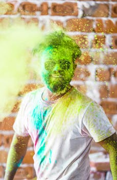 A man covered in vibrant colors celebrates the Holi festival in India with joyful expression and energy.