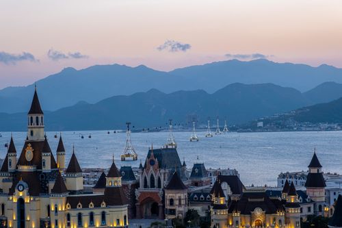 Free Vinwonders park with glowing towers located on coastal area near sea against mountain ridge in Hha Trang city in evening time Stock Photo