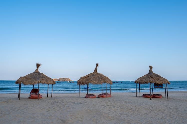 Thatched Parasols On Sandy Beach