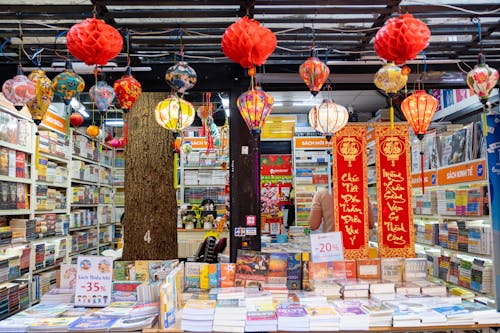 Local book shop with collection of various literature on bookshelves with traditional red decorative Chinese lanterns and hieroglyphs in city