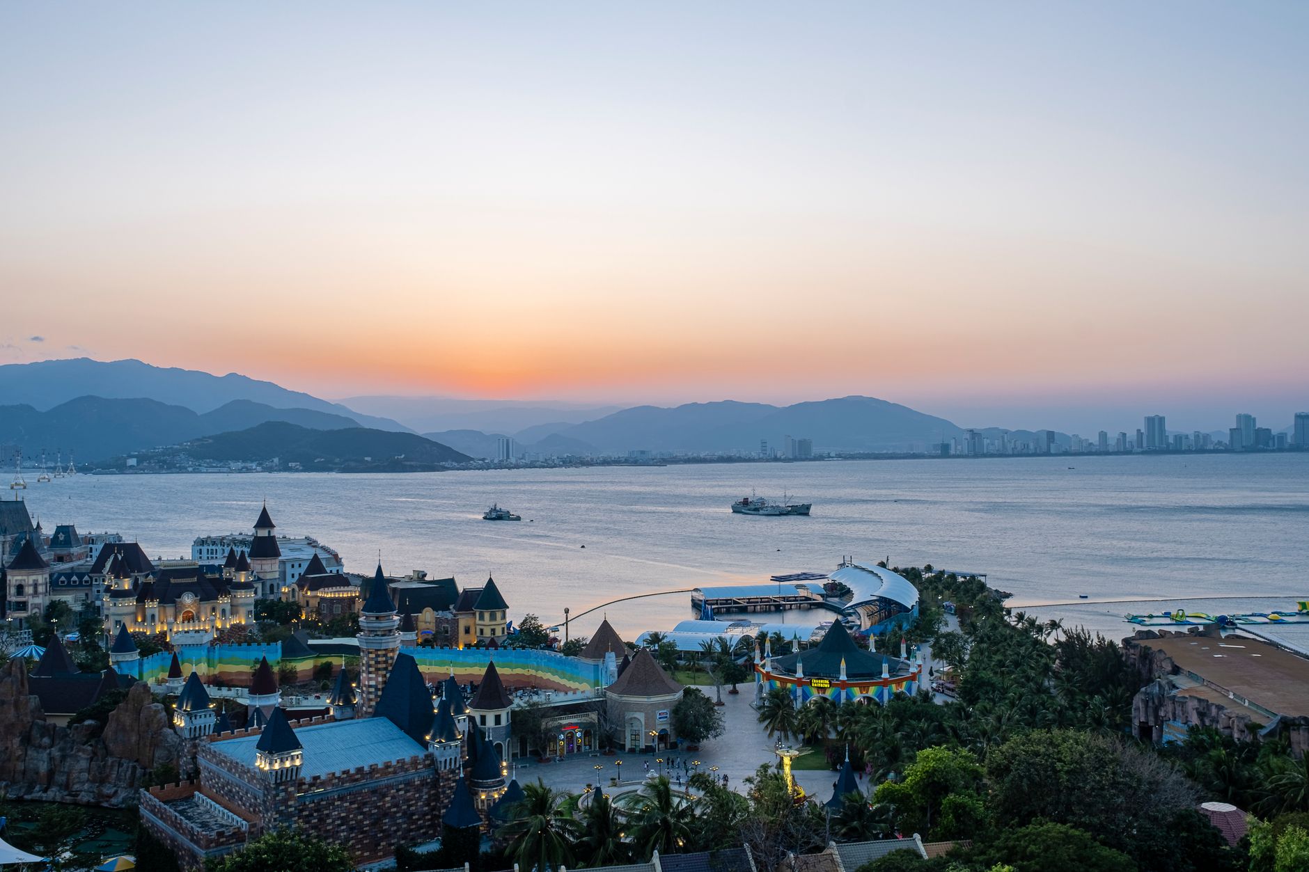 Vinwonders park with various attractions located in coastal area of Nha Trang against sunset sky and mountain ridge on s