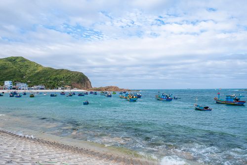 Free Picturesque view of sea coast with sandy beach near wavy water with floating boats on sunny day Stock Photo