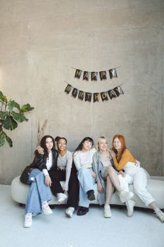 A group of young women sitting on a sofa, celebrating a birthday in a modern room.