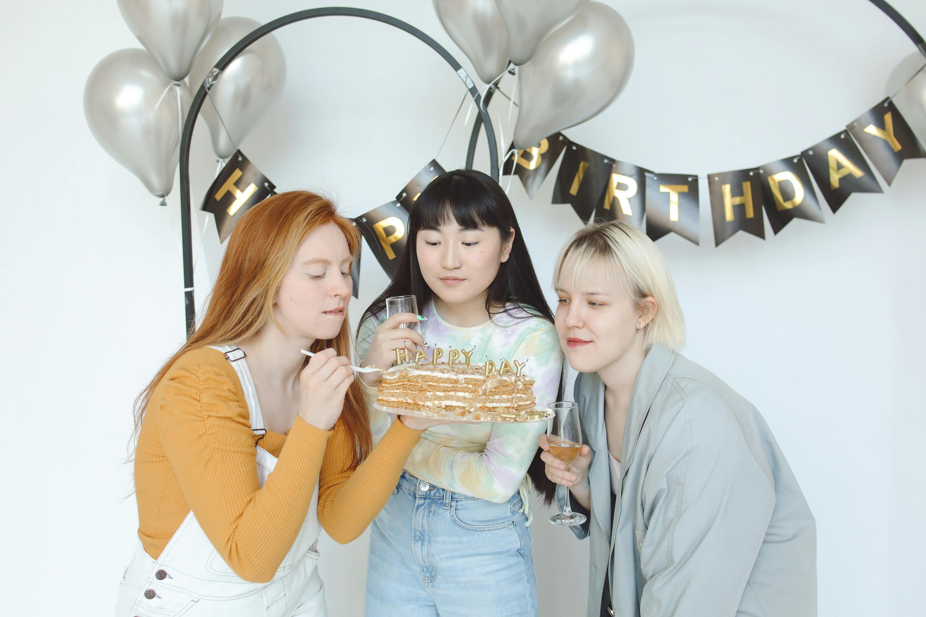 a woman holding birthday cake beside women