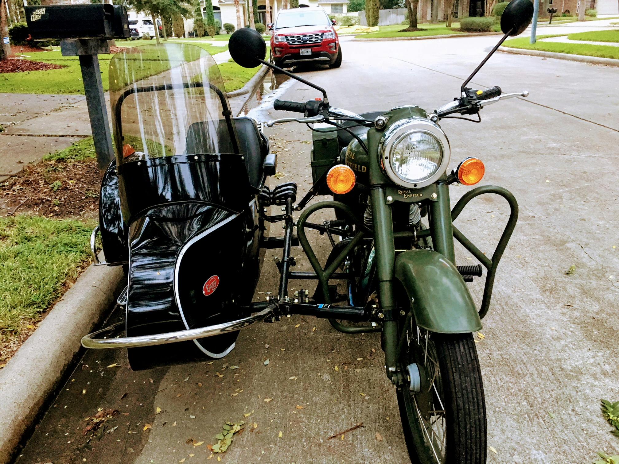 一辆经典绿色边车摩托车停在郊区街道上，展现出复古设计