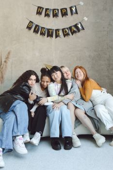 Group of diverse friends embracing during a birthday celebration indoors.
