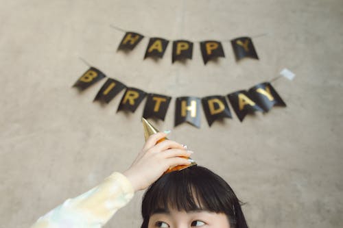 Photograph of a Girl Putting on a Party Hat
