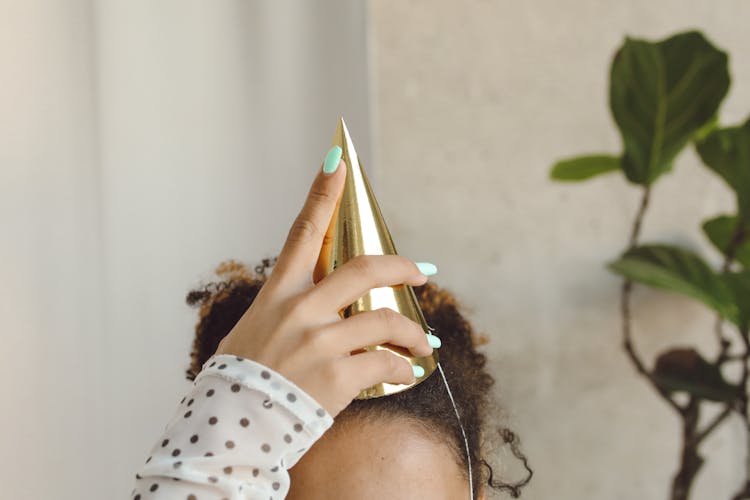 Close-up Of Woman Putting Party Hat On Head