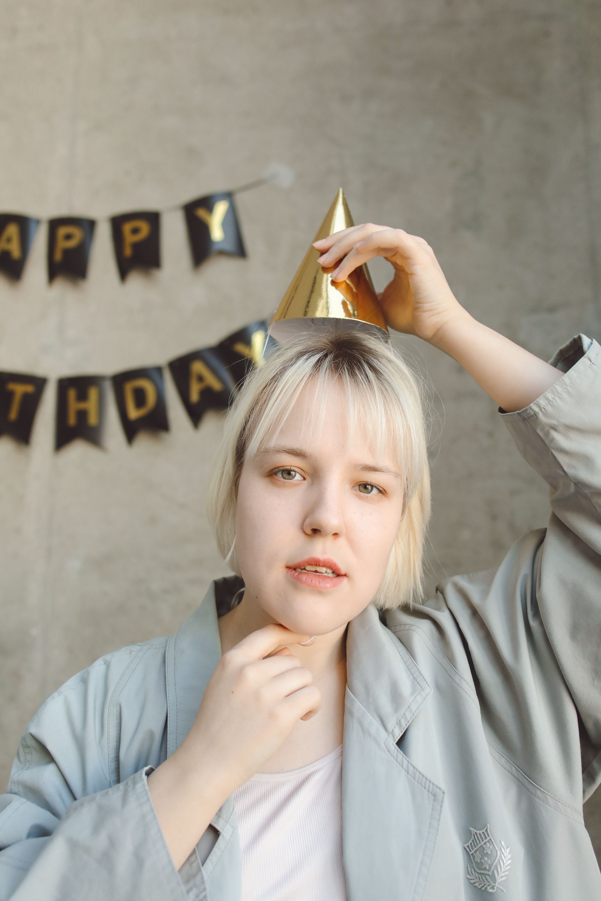 Portrait of a young woman in a party hat celebrating a birthday indoors.