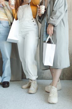 A group of women holding shopping bags and coffee cups indoors, showcasing casual fashion style.