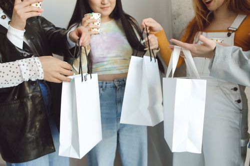 Free A group of diverse friends celebrating with drinks and exchanging gift bags indoors. Stock Photo