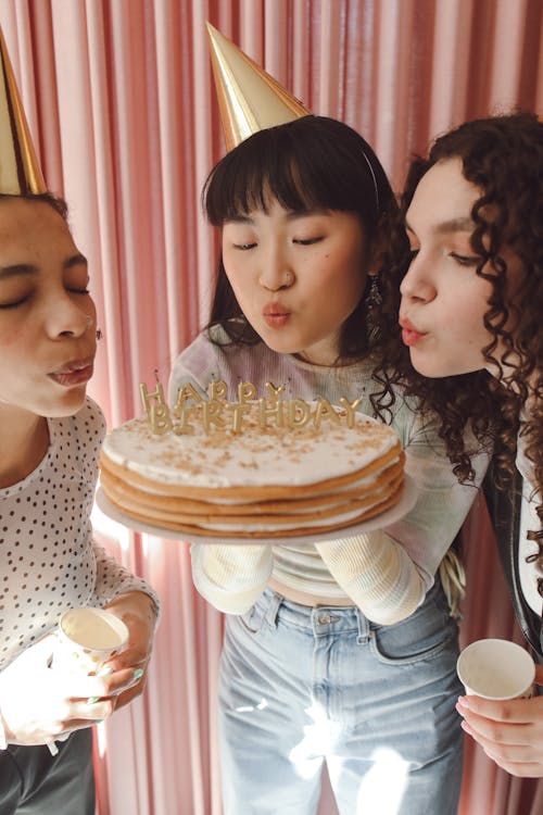 Teenagers Blowing Candles From a Birthday Cake 