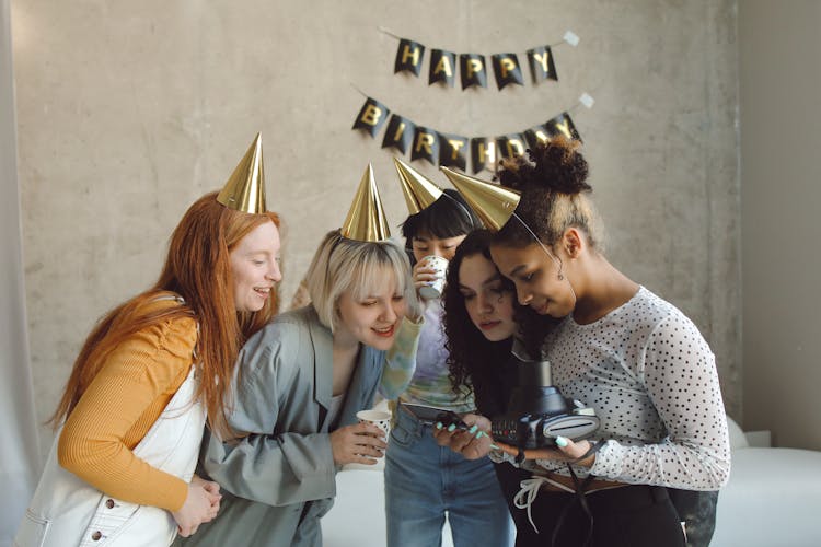 A Group Of Girls Looking At A Film Photo Together