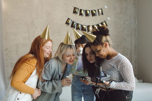Free A group of friends enjoying a birthday party with smiles, hats, and camera moments. Stock Photo