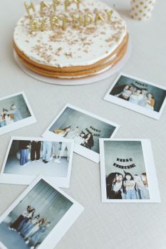 A chic birthday party setup featuring a cake and scattered Polaroid photos for capturing memorable moments.