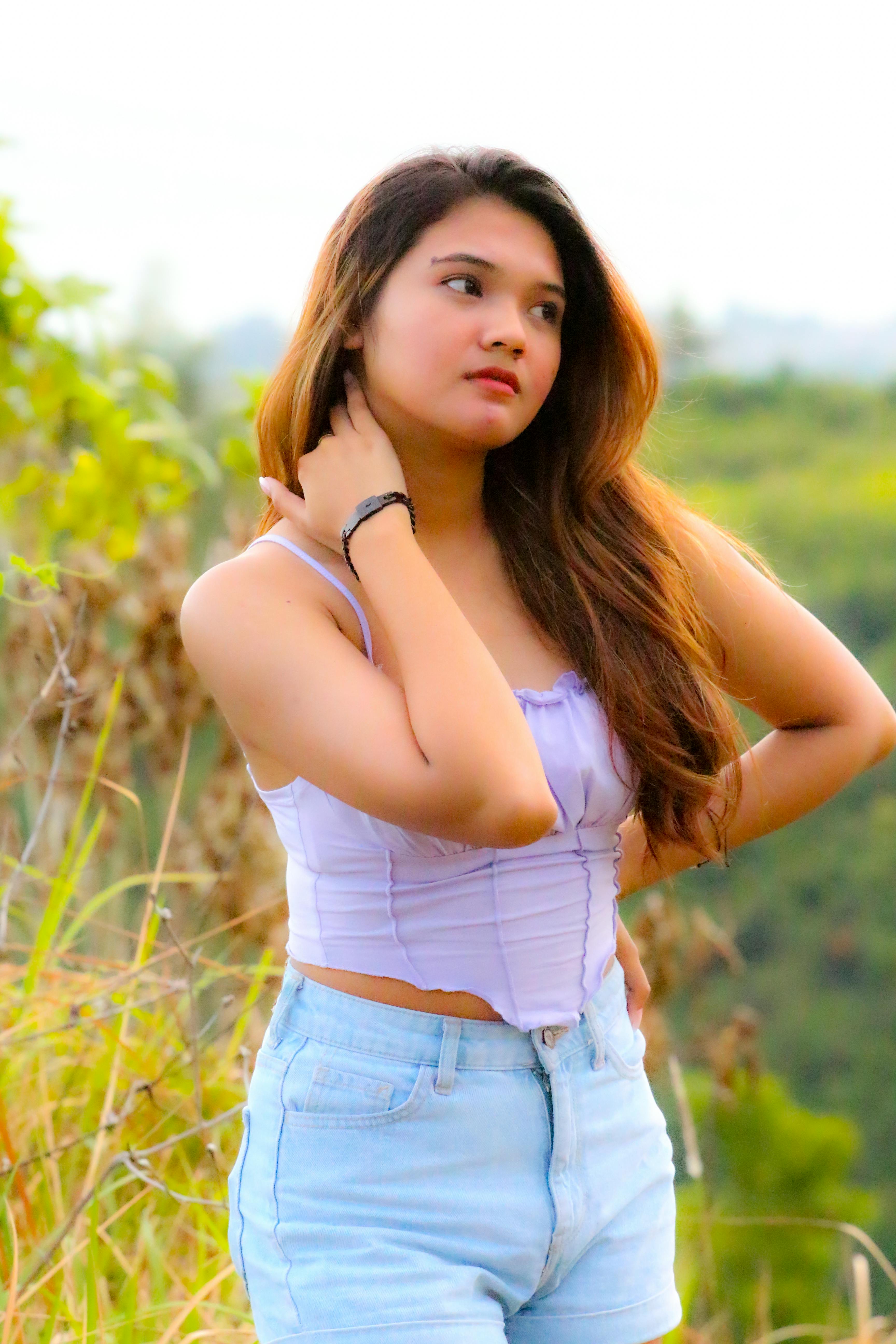 Beautiful young woman in purple top posing outdoors with blurred natural background.