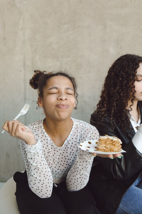 Free African American woman savoring a piece of cake indoors, eyes closed in delight. Stock Photo