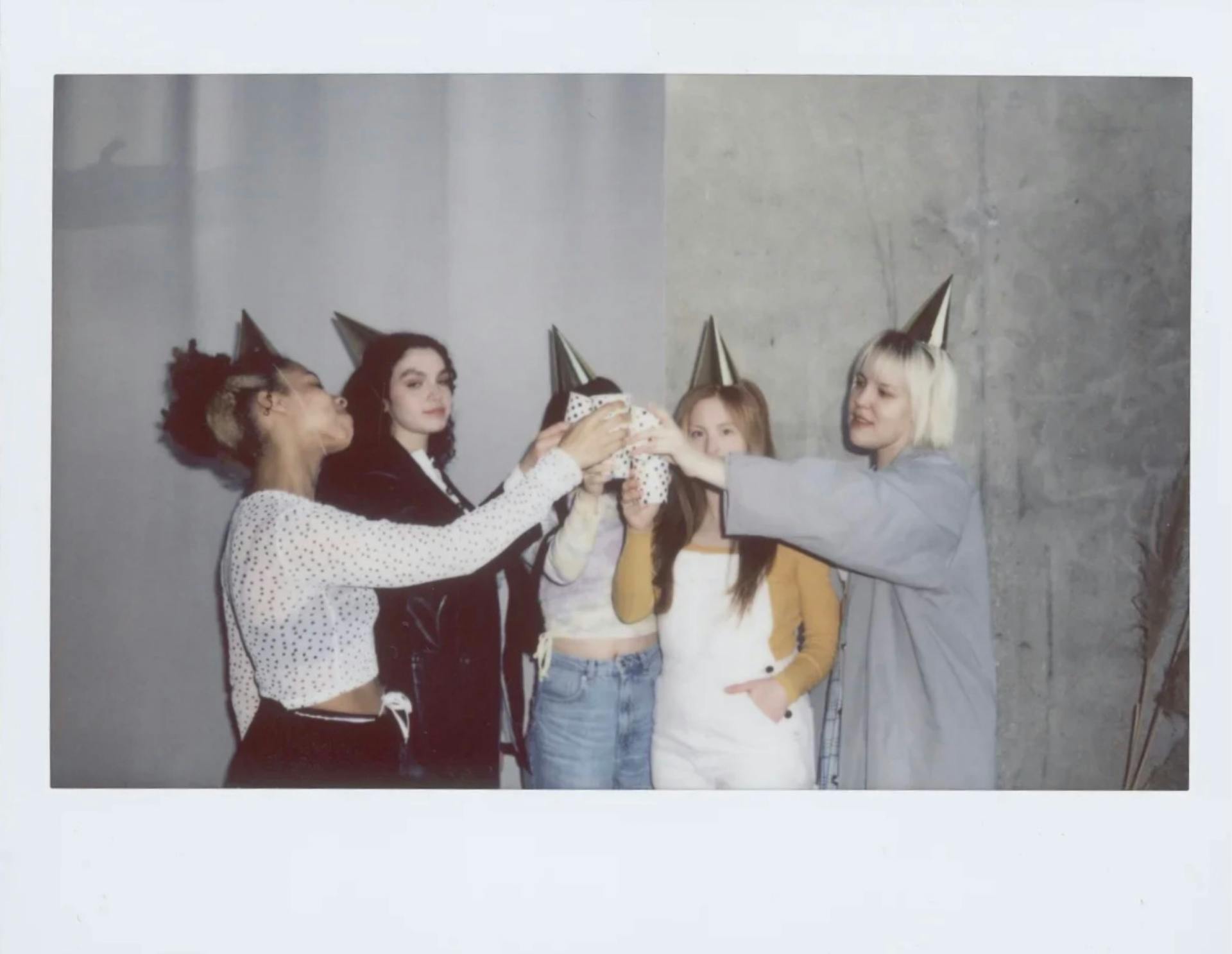 A Picture of Women Toasting while Wearing Party Hats