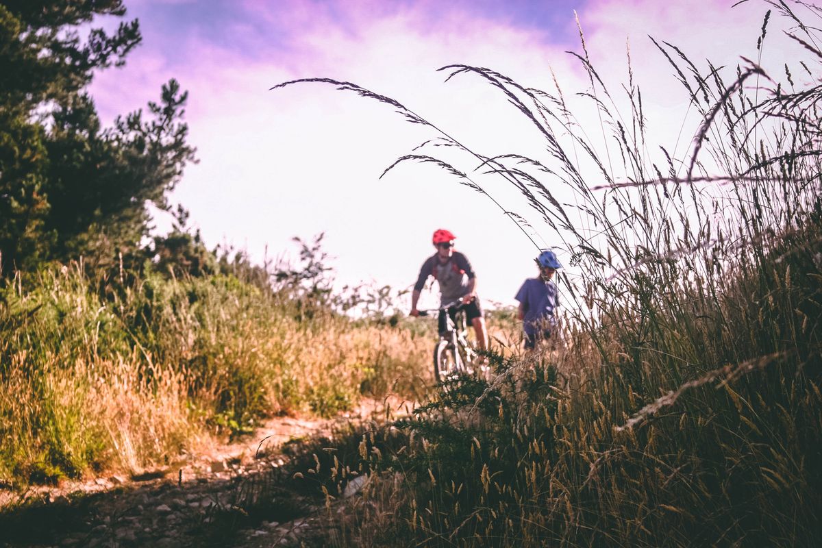 Two helmeted cyclists riding bicycles together through a scenic open landscape