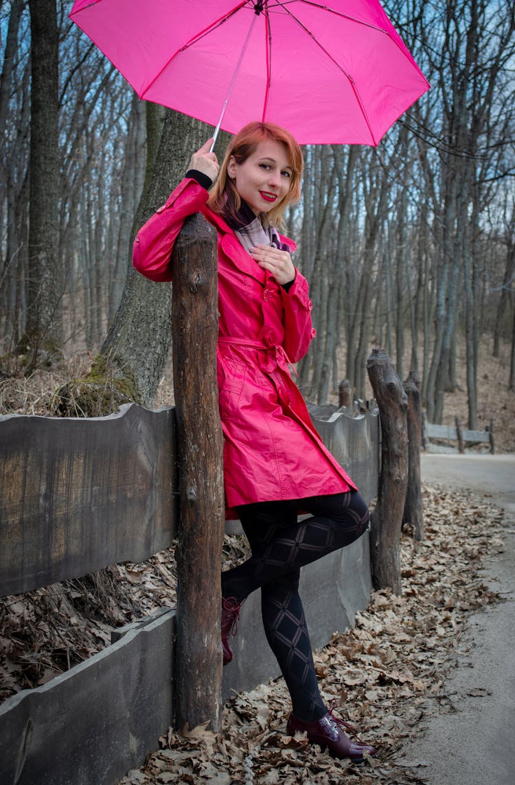 Woman In Pink Coat Near Wooden Fence