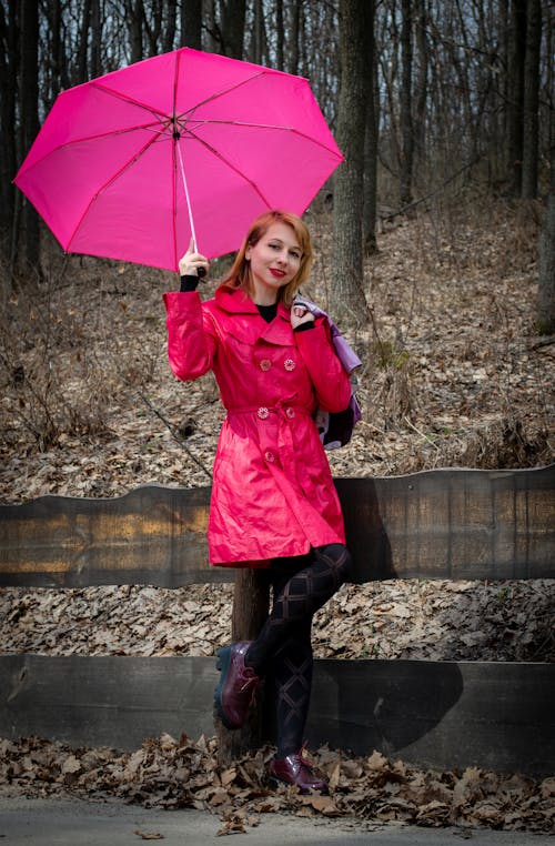 Young lady in park wearing pink attire and holding umbrella