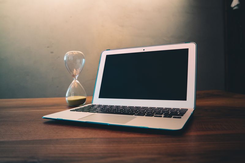 Laptop beside hourglass representing time saved through automation