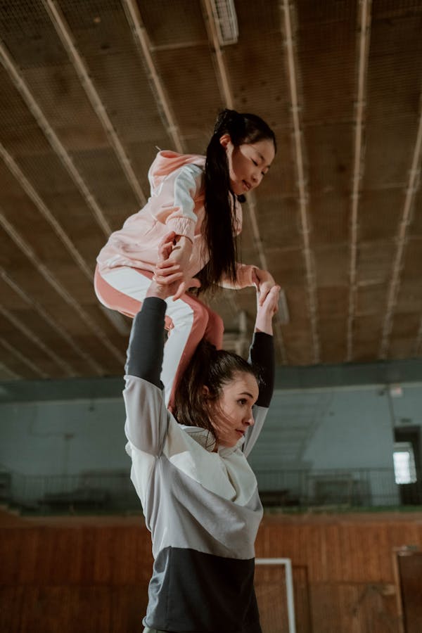 Girl Trying to Stand on Woman's Shoulders 