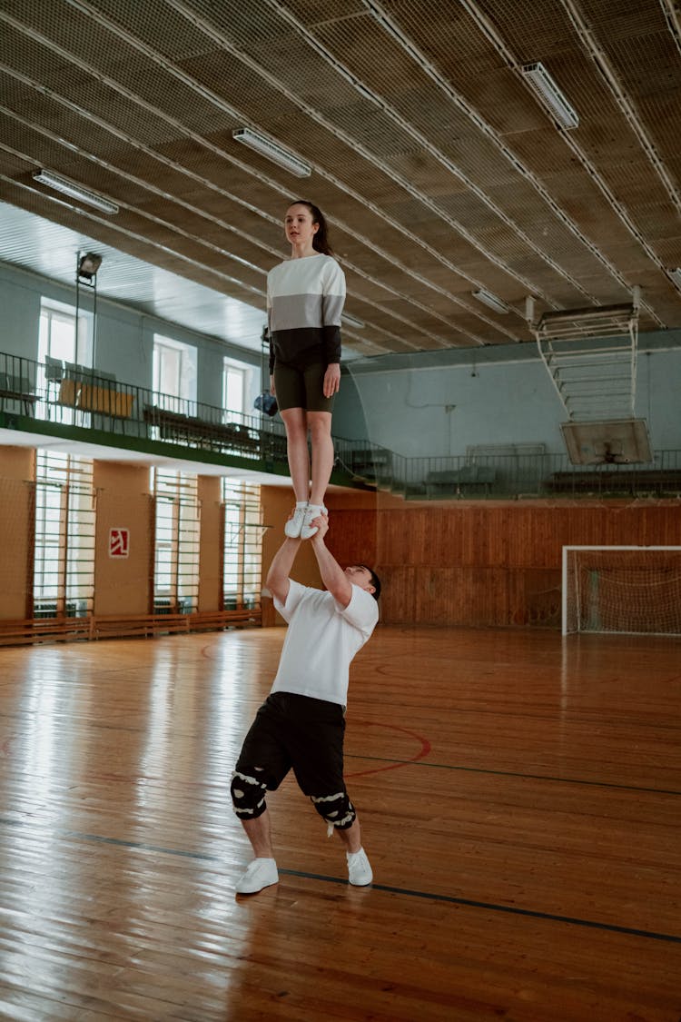 A Man Lifting A Woman Standing On His Hands