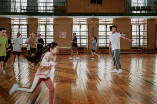 Free A diverse group of people running and training on an indoor basketball court with a wooden floor. Stock Photo
