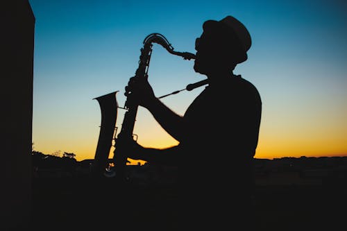 Free Silhouet Van Een Man Saxofoon Spelen Tijdens Zonsondergang Stock Photo
