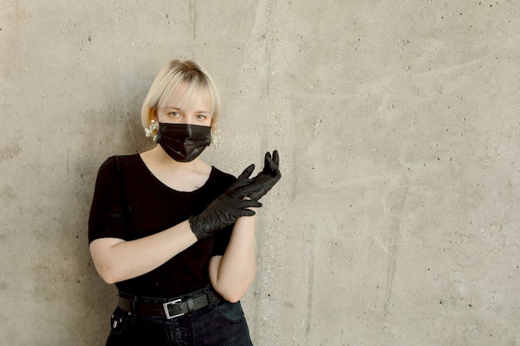 Woman In Black Shirt And Denim Jeans Wearing Disposable Gloves