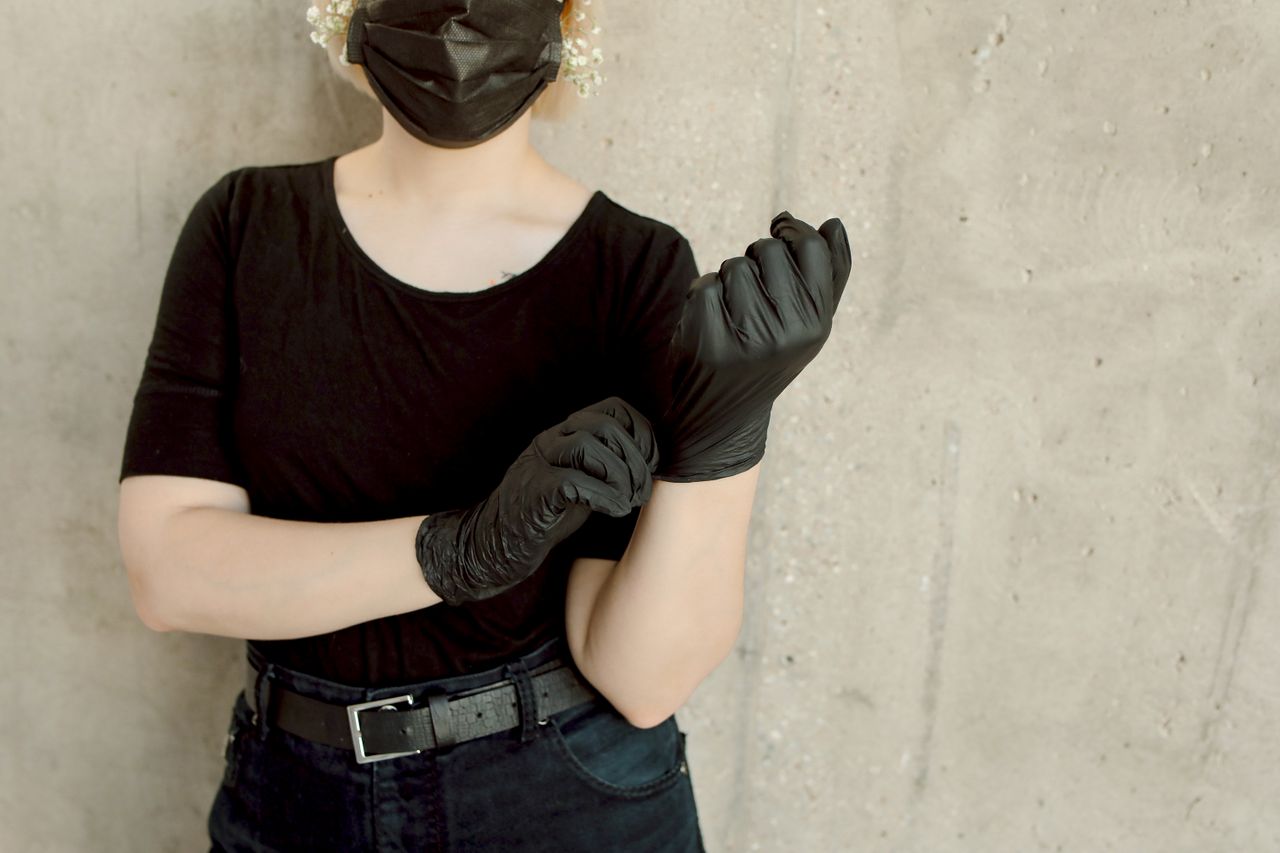 a woman in black attire fits gloves against a concrete wall backdrop e