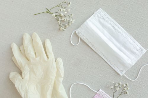 Free Flat lay of a face mask, latex gloves, and flowers, symbolizing protection and care. Stock Photo