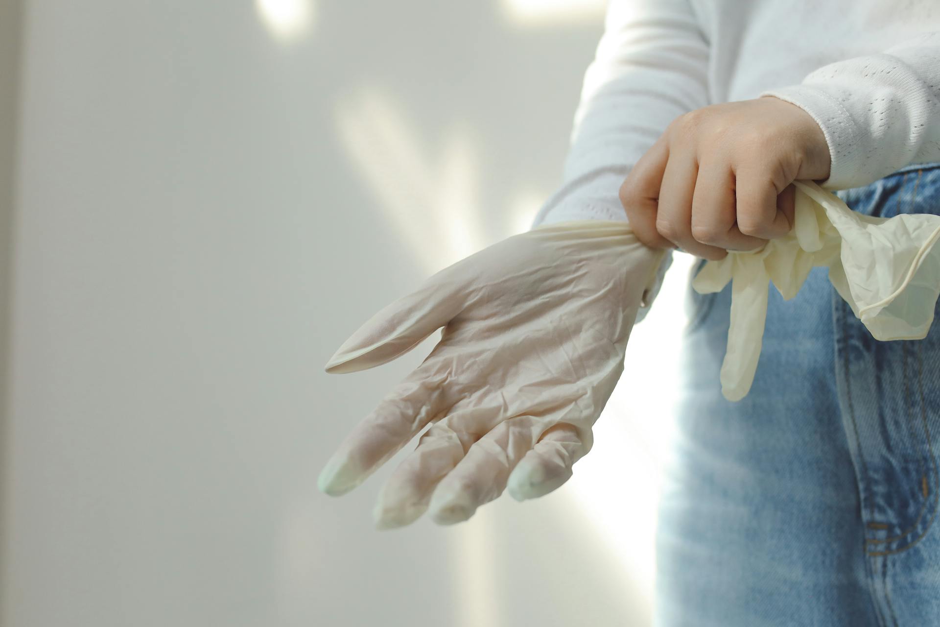 Person in Blue Denim Jeans Holding White Latex Gloves
