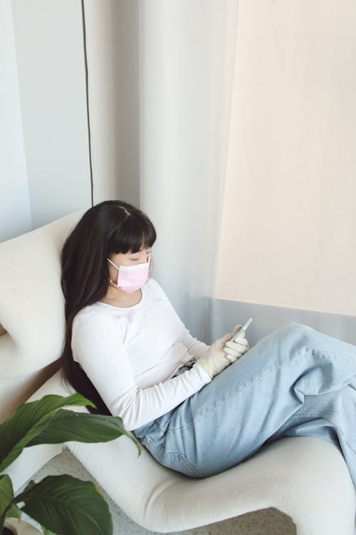 A Woman in White Long Sleeve Shirt and Blue Denim Jeans Wearing Face Mask