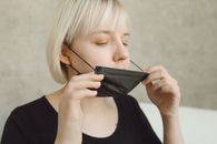 A Woman in Black Shirt Removing Her Face Mask