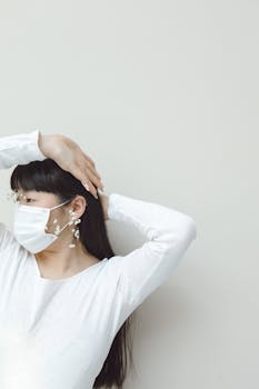 A young woman in a stylish mask, posing indoors with floral decorations.