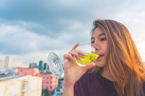 Free Woman in Purple Top Drinking on Clear Wine Glass Stock Photo