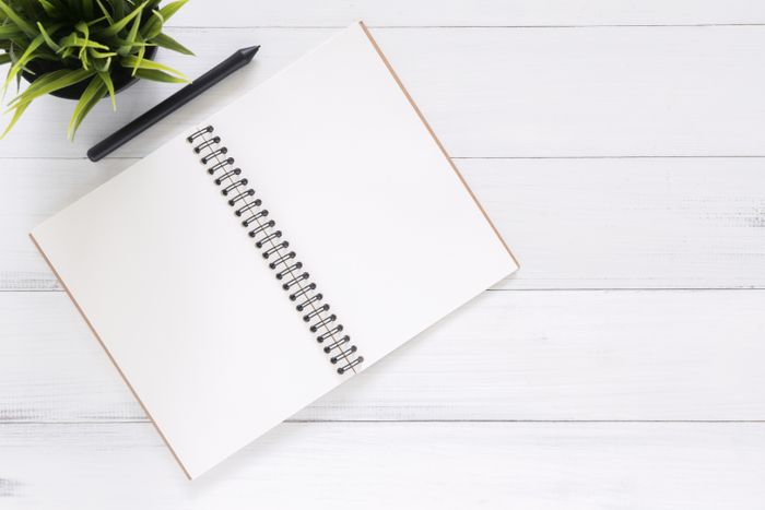 Open notebook and pen on a pale desk — Tirachard Kumtanom on Pexels