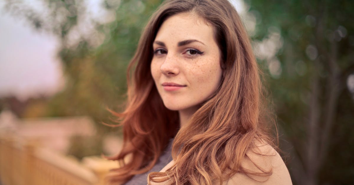 A young woman with long hair smiles confidently for an outdoor portrait session.