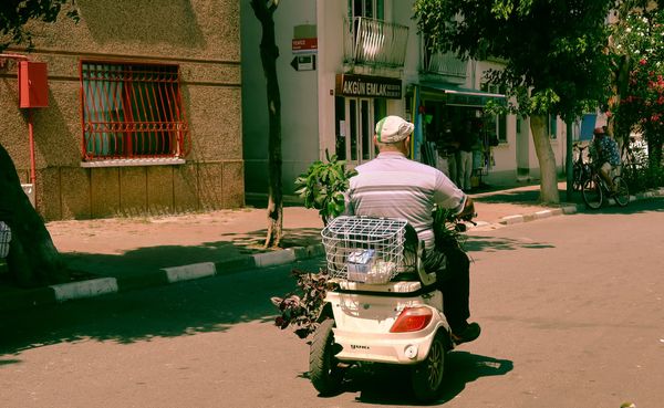 Senior rider on a mobility scooter with a rear basket on a sunny street