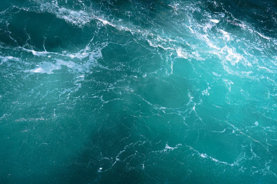 Vibrant turquoise ocean waves creating a mesmerizing natural texture from above.
