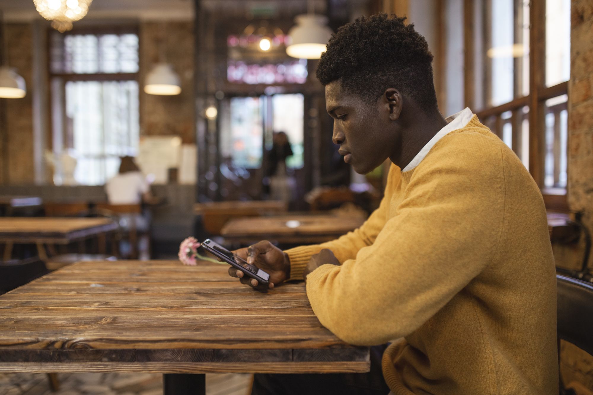 Persona sentada en la mesa de un restaurante consulta una app de búsqueda de negocios en su teléfono
